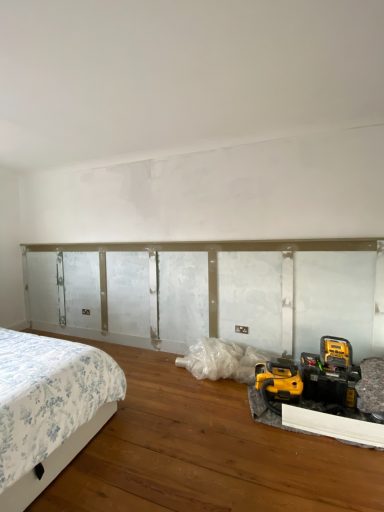 Progress of wall panelling that has primed and filled for sanding with tools stored next to it on a wooden floor
