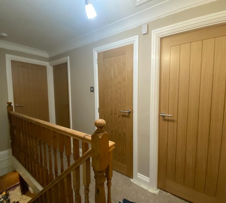 A hallway with wooden doors on three sides and a wooden railing.