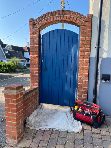 Blue wooden door set in a brick archway with a toolbox on the ground.