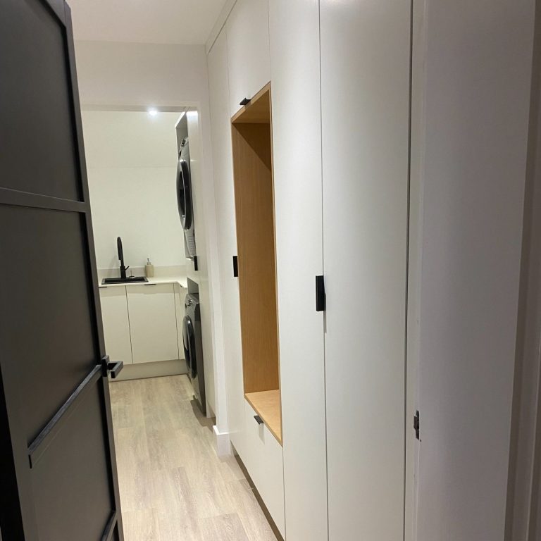 A narrow hallway with white walls and a built-in storage unit.