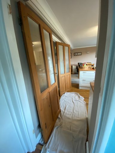 Wooden doors with glass panels, leading to a room with light-coloured furniture.